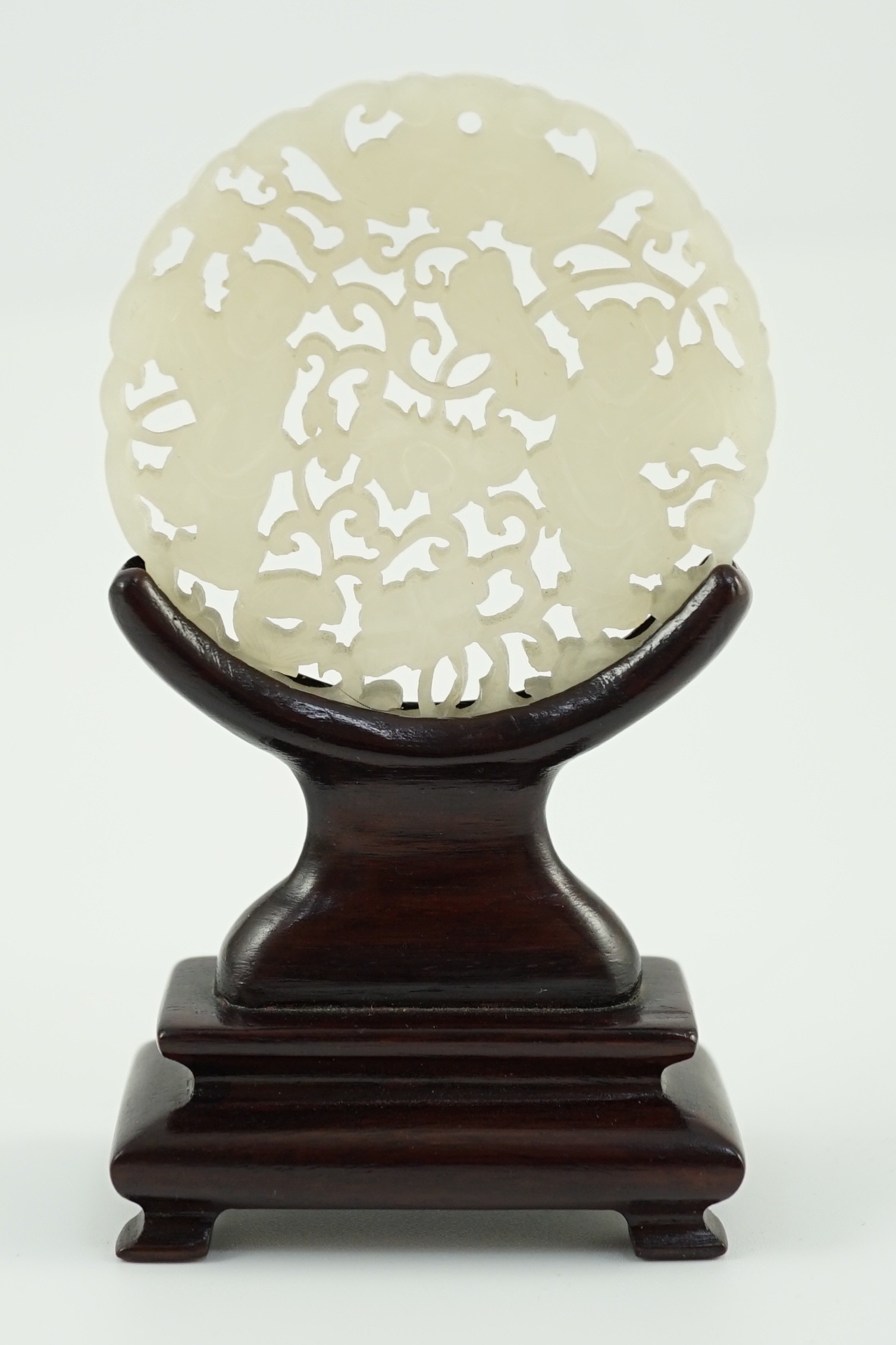 A Chinese white jade ‘Hehe Erxian’ disc, 19th/20th century, 5.6cm diameter, wood stand